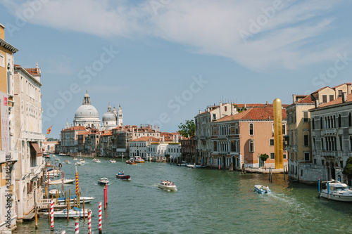 Street of Venice in summer time. Italian view. Roof, sea canal, boat in sunny day. Old city, ancient buildings.  Italy. Basilica Santa Maria della Salute. Popular tourist destination of Italy. Europe. © Svetlana