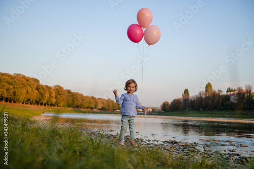 Holiday with a little girl. Little girl on the nature with balloons. Emotions and joy