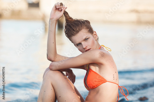 A young beautiful girl poses in a swimsuit on the beach