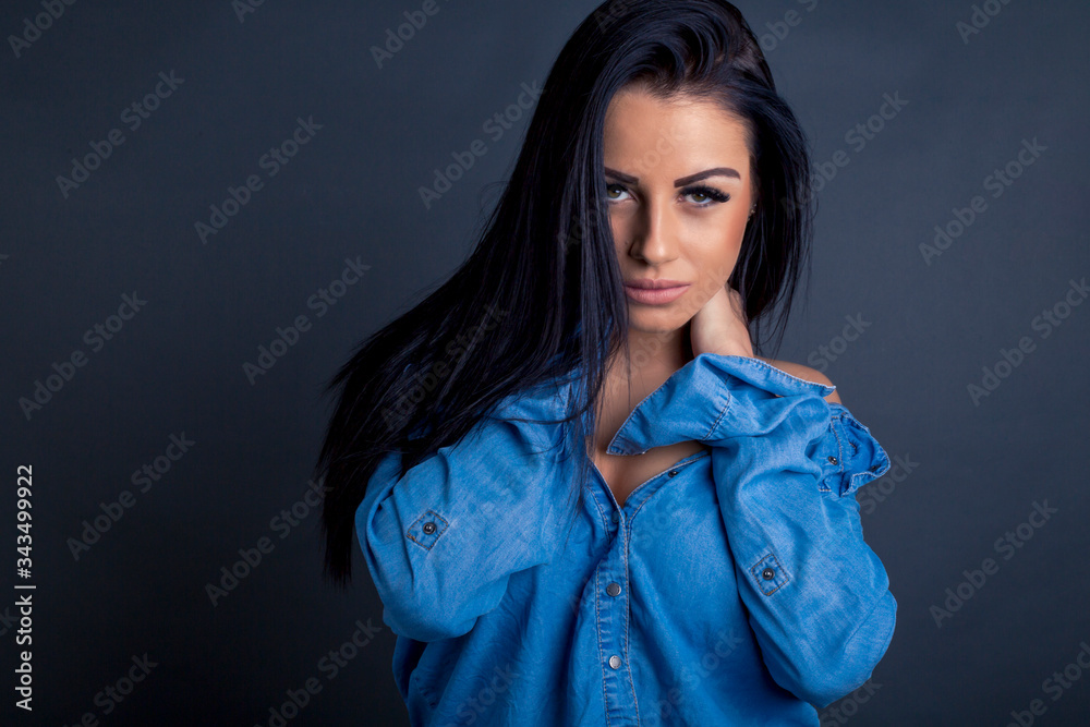 Attractive brunette woman posing to camera in blue shirt