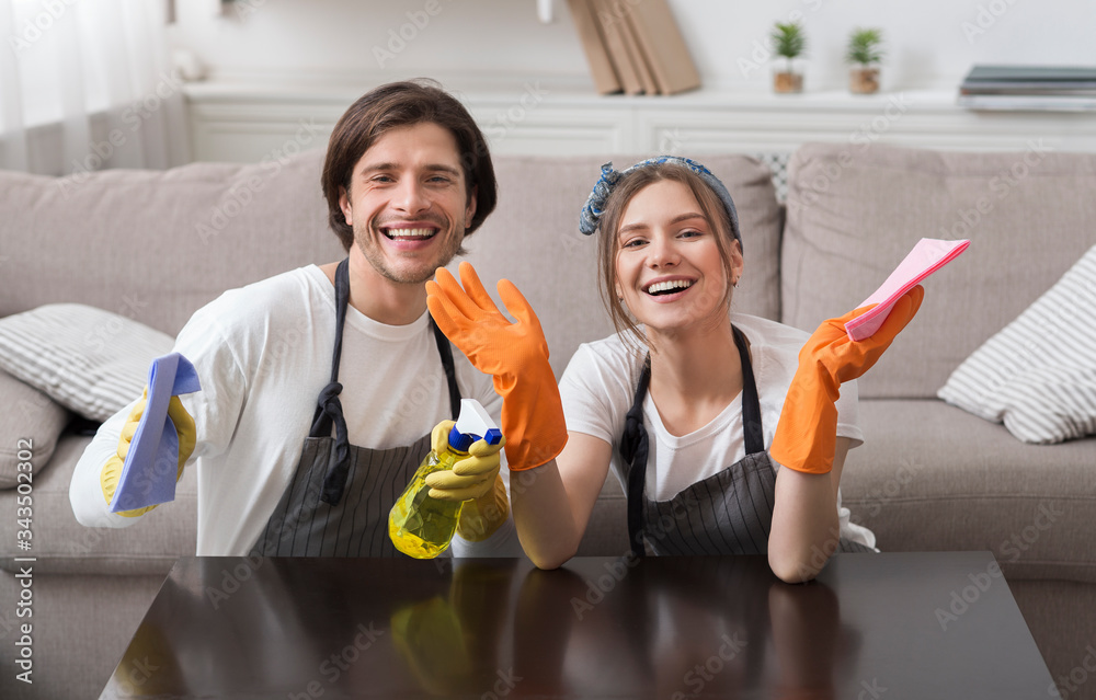 Joyful young couple posing while cleaning up house together