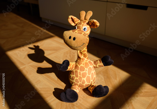 Photography Cute standing giraffe stuffed plush in a child's room illuminated by sunlight coming from the window and casting a nice shadow over the floor