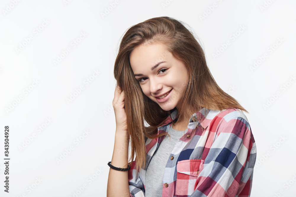Smiling teen girl touching her hair looking at camera Smiling teen girl touching her hair looking at camera