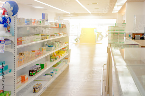 Medicines arranged in glass shelves, Pharmacy drugstore retail Interior blur abstract background with medicine healthcare product on cabinet with warm light. © kamol