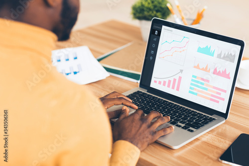 Black entrepreneur analyzing graph on laptop at workplace photo