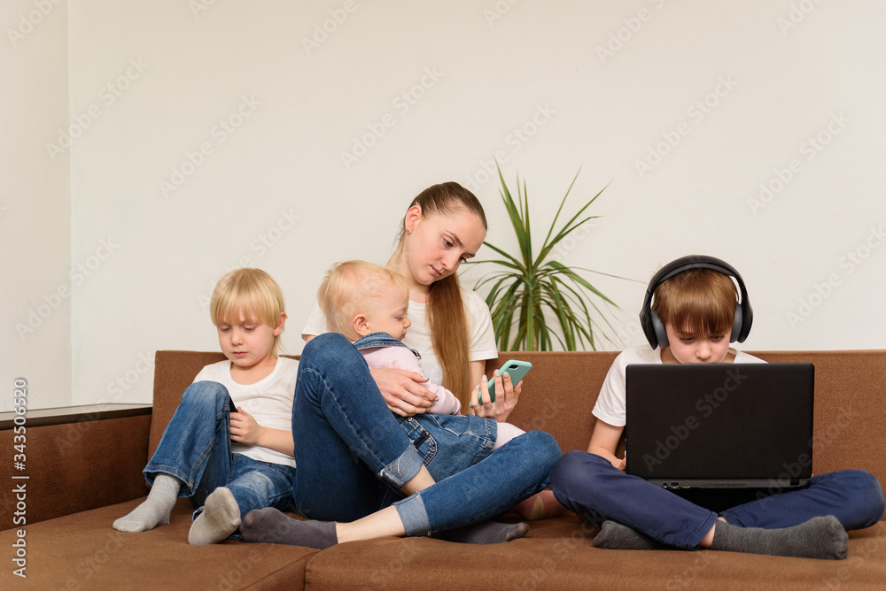 Four siblings sit on couch and use laptop and phones. Generation Alpha concept