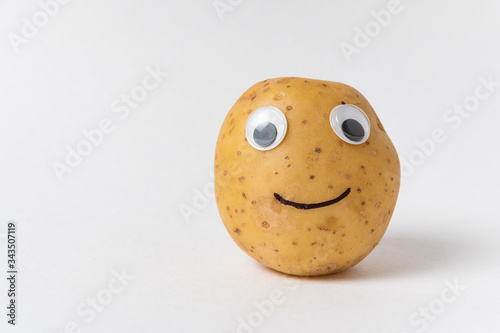 Fotografiet Funny raw potatoes with Googly eyes and smile on white background