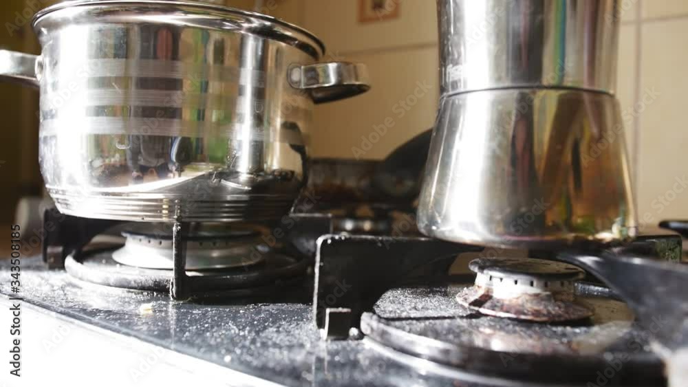 Geyser coffee maker and saucepan on gas stove.