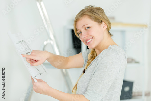 young woman pointing at blueprint for decorating idea © auremar