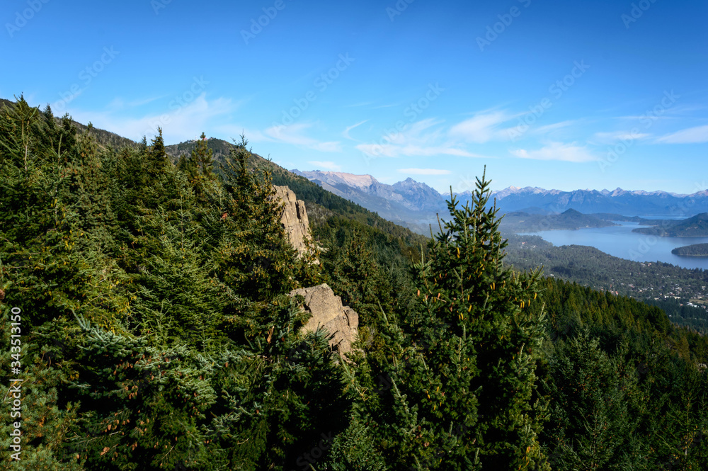 Landscape with lakes between mountains and pine trees. On top of a mountain in Bariloche, Argentina. A sunny summer day.