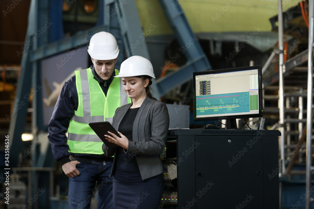 custom made wallpaper toronto digitalPortrait of a female factory manager in a white hard hat and business suit and factory engineer in work clothes. Controlling the work process at the airplane manufacturer.