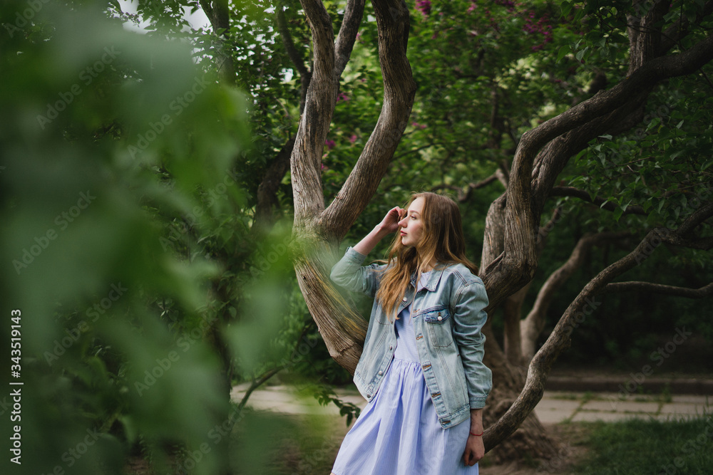 Romantic and beautiful caucasian girl in casual clothes hugging on the background of beautiful blooming lilac. Young woman walking outdoors in spring park. Romantic and beautiful caucasian girl in casual clothes hugging on the background of beautiful blooming lilac. Young woman walking outdoors in spring park.