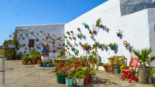 VEJER DE LA FRONTERA, SPAIN - 06.21.2018: Flower Pots with geraniums on a white wall of a spanish andalusian town photo