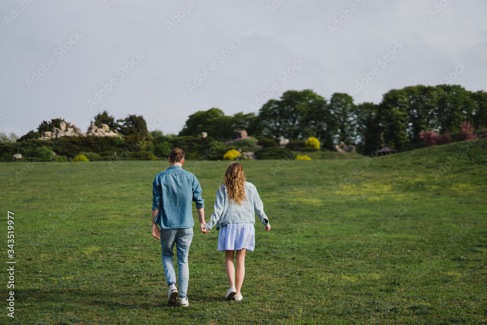 Romantic and happy caucasian couple in casual clothes hugging on the background of beautiful blooming trees. Love, relationships, romance, happiness concept. Man and woman walking outdoors together. Romantic and happy caucasian couple in casual clothes hugging on the background of beautiful blooming trees. Love, relationships, romance, happiness concept. Man and woman walking outdoors together.