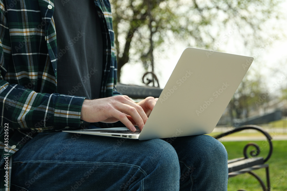 Man with laptop works in park. Outdoor work