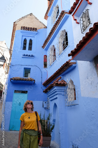 Middle-aged pretty female tourist traveling in the kasbah - old part of city Chefchaouen, Morocco. © leospek