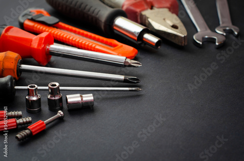 A Set of a lot of different red tools for working include hammer wrench bit pliers, screwdriver, paper knife, screwdriver nozzle, key on black background 