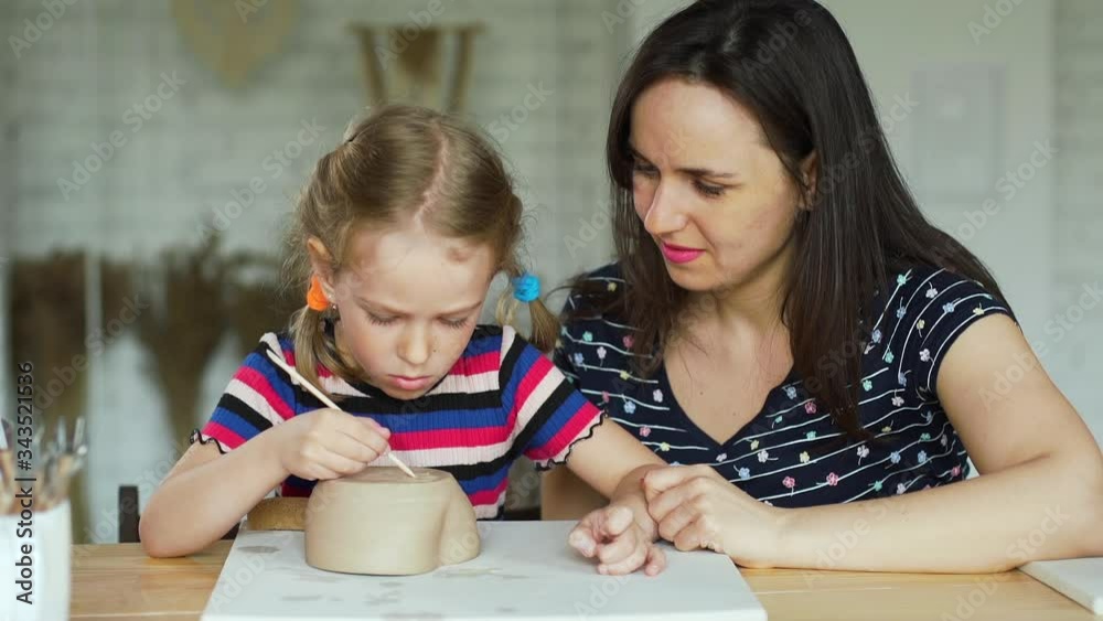 Little Girl with Mother Working on a Clay Dish in a Pottery Class. Concept of Art, Hobby and Activities for Children Little Girl with Mother Working on a Clay Dish in a Pottery Class. Concept of Art, Hobby and Activities for Children