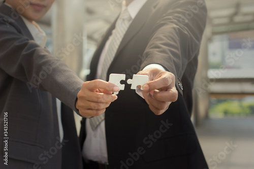 Positive sign for business solution : Picture of businessman and businessowoman able to match jigsaw.