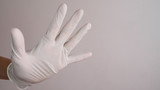 Stopping the disease. Prevention of viruses. Hand in white sterile latex surgical glove gives a stop sign. Negative space. Copy space for text.