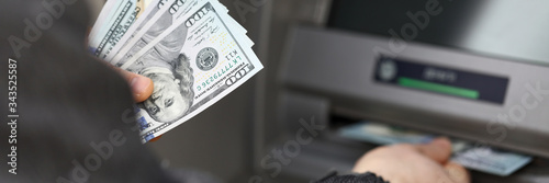 Man stand near terminal and withdraws cash dollars