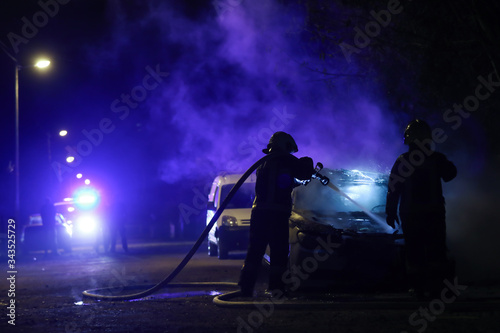 firefighters fighting against the fire in the midnight. Police car in a back. 