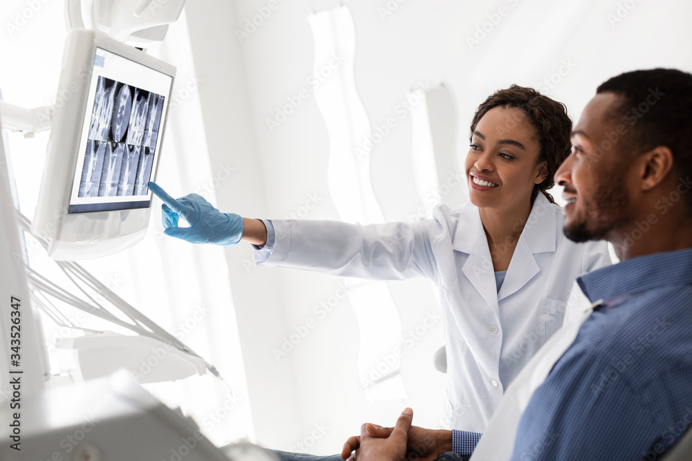 Friendly dentist showing patient his teeth on xray