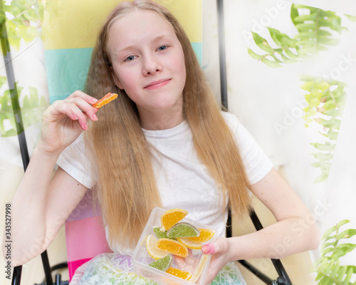 The teen girl sits in beach chair and hold the marmalade different colors in her room