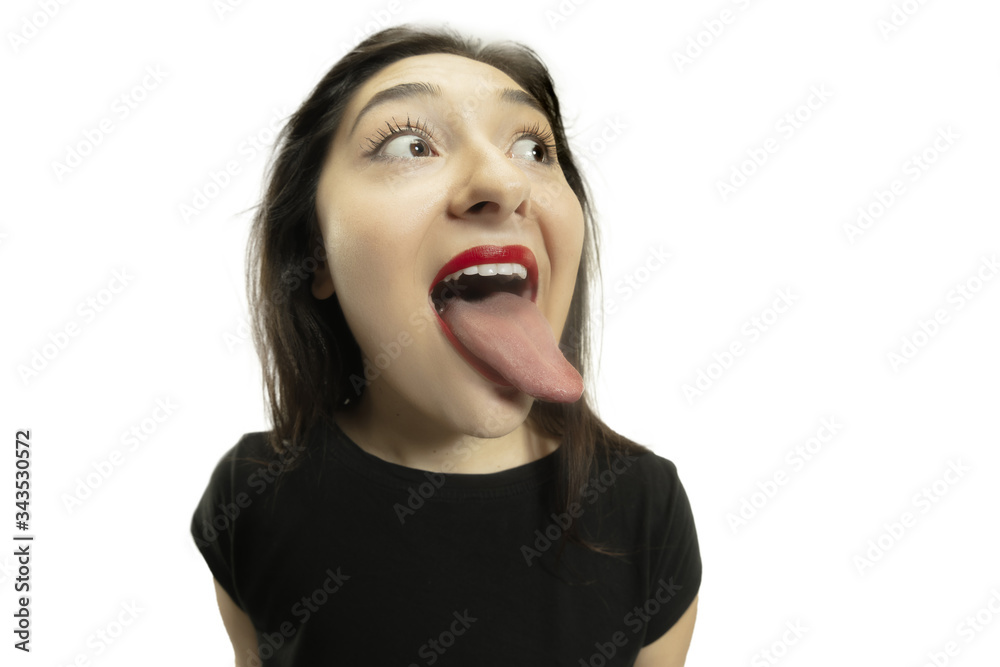 Smiling girl opening her mouth and showing the long big giant tongue isolated on white background. Looks shocked, attracted, wondered and astonished. Copyspace for ad. Human emotions, marketing. Smiling girl opening her mouth and showing the long big giant tongue isolated on white background. Looks shocked, attracted, wondered and astonished. Copyspace for ad. Human emotions, marketing.