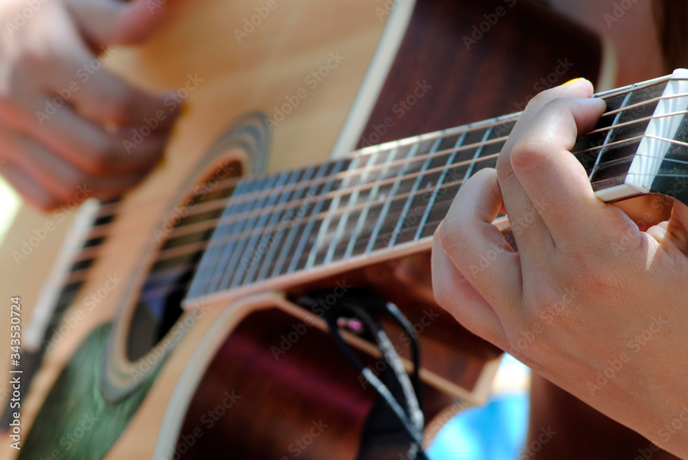 Fototapeta premium Hands of a young woman playing a Spanish guitar closeup.