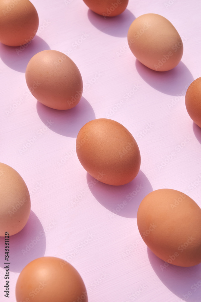 Chicken eggs on a pink background with sunlight and shadows