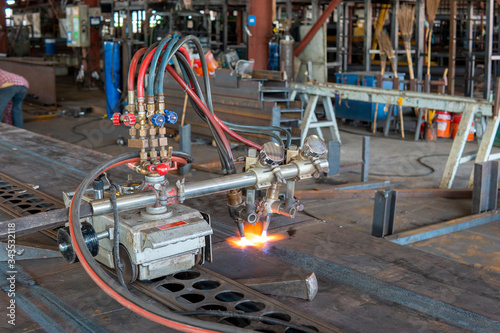 Using gas cutting machines to burning bending steel plates that is curled after welding for built-up h-beam at industrial factory.