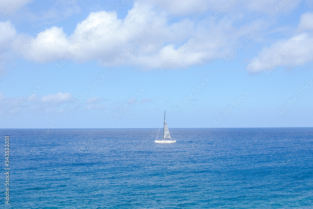 blue sky background with white big fluffy clouds and a boat in the sea 