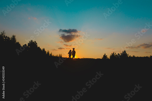 Silhouette of happy boy and girl run at sunset