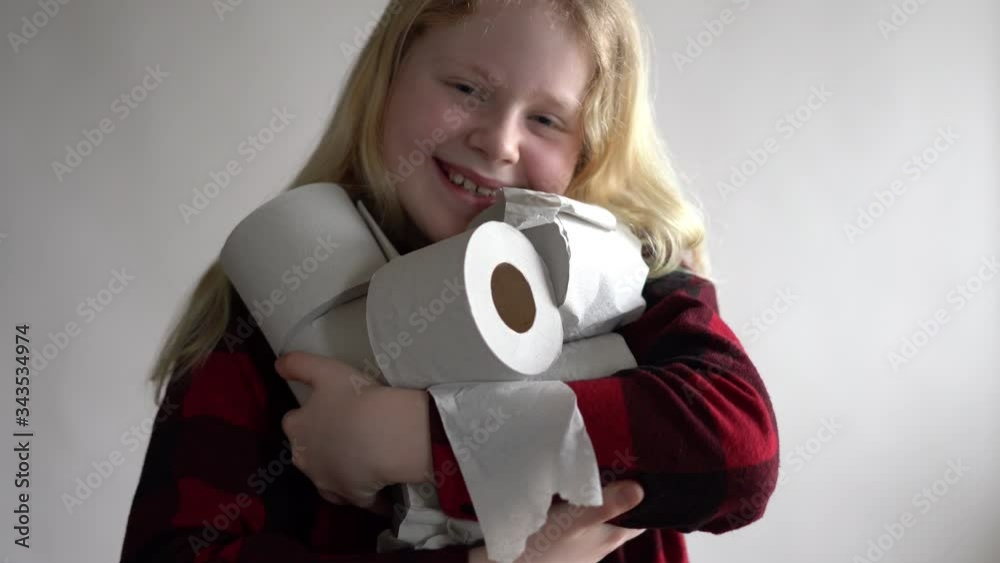 funny video - quarantined due to an epidemic of coronavirus. masked girl with rolls of toilet paper posing on gray background. funny video - quarantined due to an epidemic of coronavirus. masked girl with rolls of toilet paper posing on gray background.