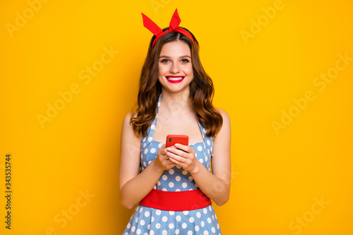 Portrait of cute sweet lovely pretty girl use smartphone chilling blogging posts wear vintage style polka-dot headband blue outfit isolated over bright shine color background