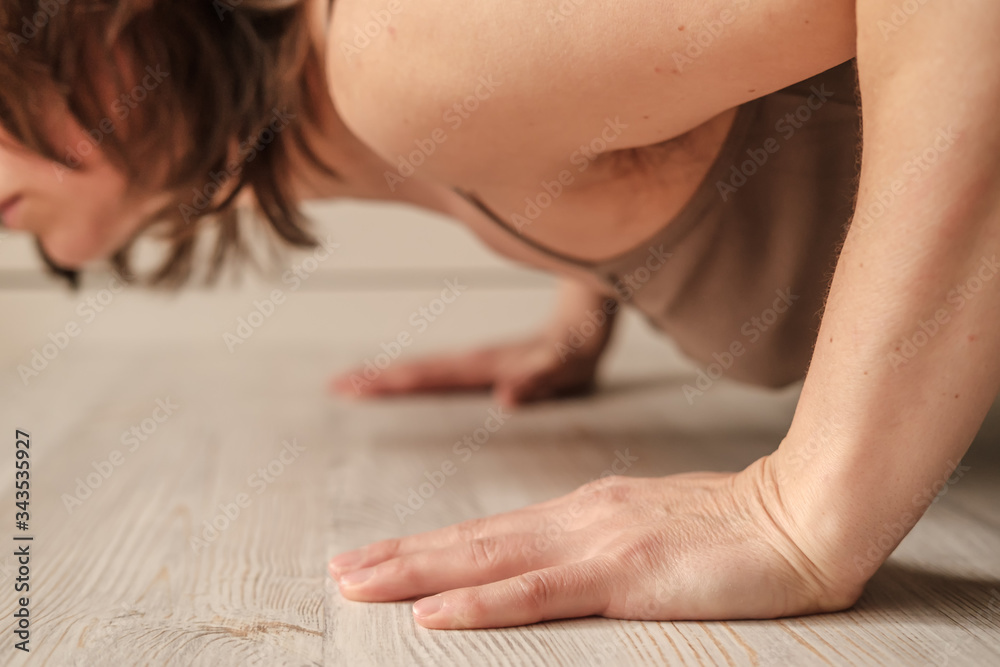 Woman doing push-ups exercise on hands or practicing yoga at home. Close-up of hands. Body positive trend. Woman doing push-ups exercise on hands or practicing yoga at home. Close-up of hands. Body positive trend.
