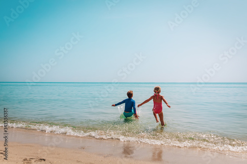 happy boy and girl run swim on beach