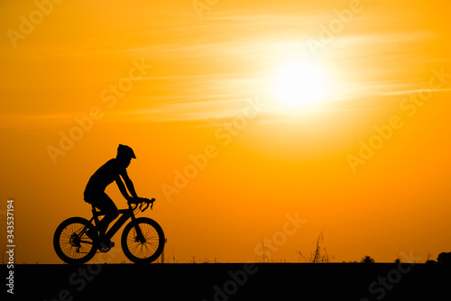 Silhouette man cycling on sunset background
