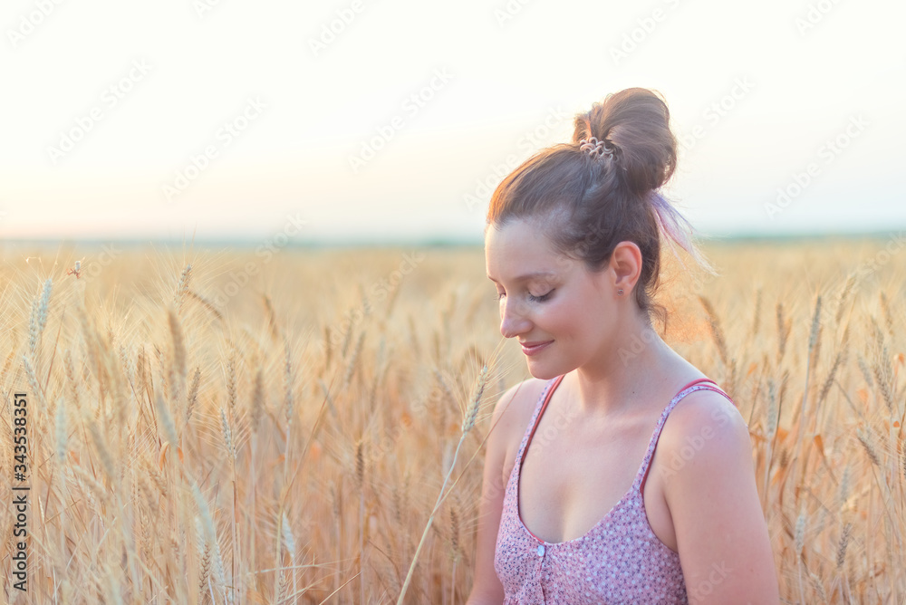 cheerful woman with long brunette hair and closed eyes in wheat field at sunset cheerful woman with long brunette hair and closed eyes in wheat field at sunset