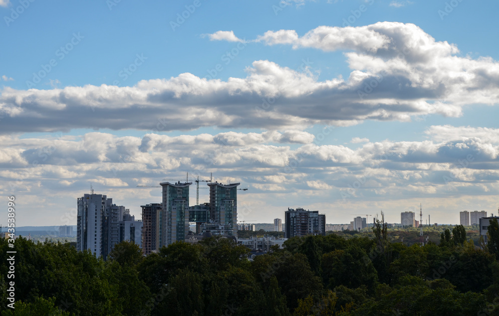 View of modern residential area against the background of cloudy sky and lush foliage in summer. Urban skyline of Kyiv city, Ukraine