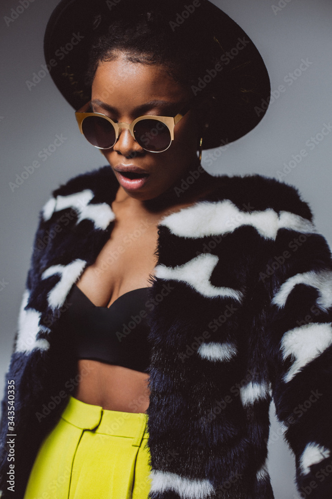 Portrait of an african woman with sunglasses and a black hat in the studio on a white background . Emotional portrait of black fashionable woman Portrait of an african woman with sunglasses and a black hat in the studio on a white background . Emotional portrait of black fashionable woman