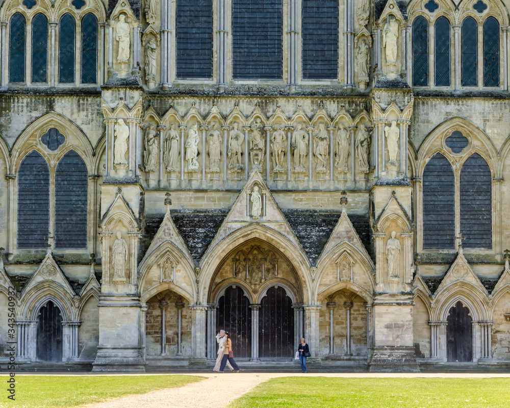 Detail of the Great West Front of Salisbury Cathedral with passers-by offering a reference of scale, Salisbury, Wiltshire, UK