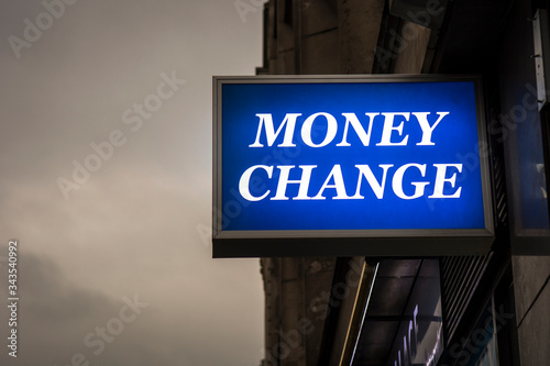 A 'Money Change' sign illuminated on city street