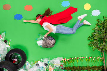 Full body flat lay photo activist lady take care of nature sorting cleaning plastic saving plants super woman concept fly air under trash hold big garbage bag isolated green color background