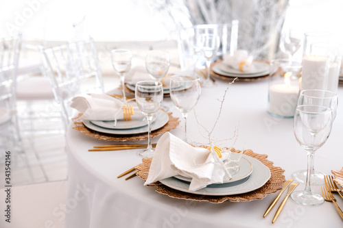 Luxurious stylish decoration of the wedding table for the winter wedding. Fresh and dried white flowers. Beautiful table setting: golden appliances, fork and knife, feather. Winter Concept