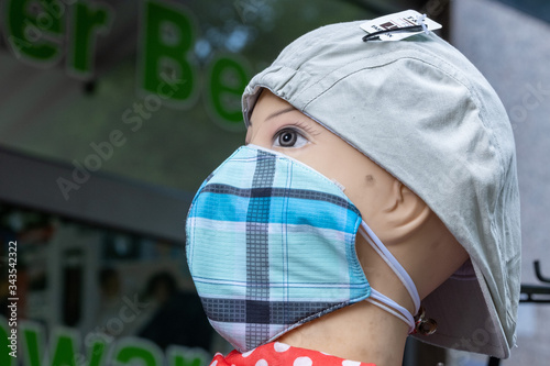 Schaufensterpuppe mit Mütze und einem mund-Nasen-Schutz vor einem Bekleidungsgeschäft in Berlin photo