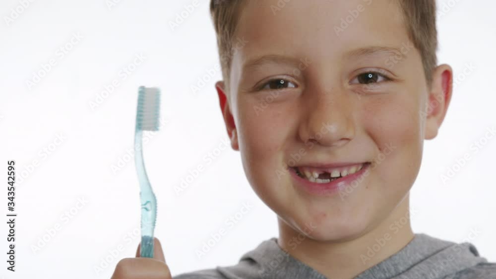 Closeup portrait happy smiling boy holding a toothbrush. Cheerful boy without a front tooth. Closeup portrait happy smiling boy holding a toothbrush. Cheerful boy without a front tooth.