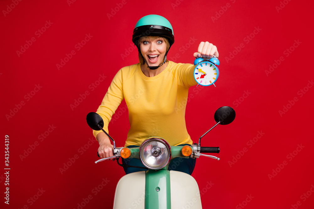 Portrait of excited energetic girl ride her fast speed motorbike hold show watch enjoy her sporty racing result wear yellow pullover isolated over bright shine color background