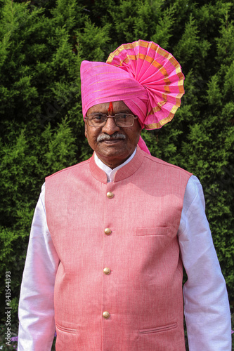 Old Indian grandfather wearing pink color turban and giving pose for photo